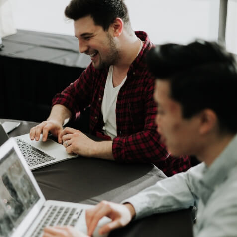 Two men working on their laptops together.